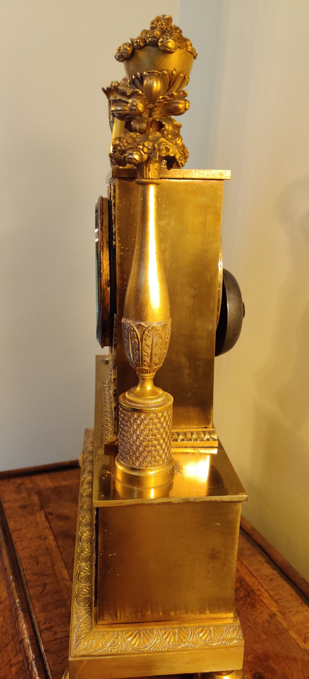 A 19th-century French gilt bronze figural mantel clock featuring a draped female classical figure beside a rectangular clock casing topped with an ornate urn finial. View VIII