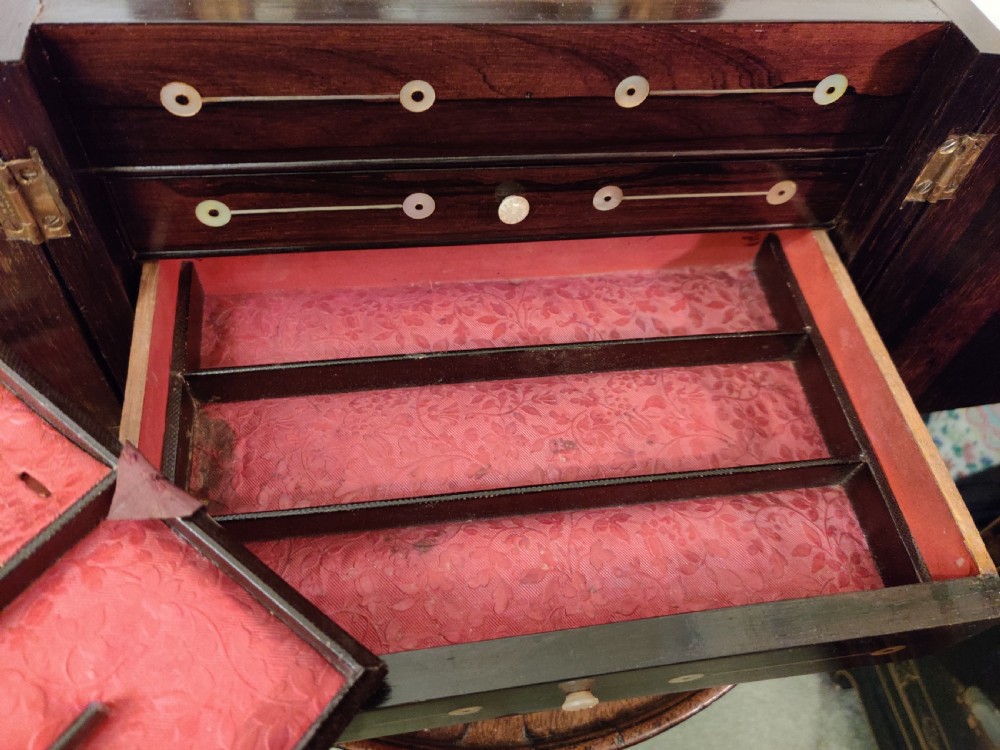 A Georgian dark rosewood tabletop cabinet featuring mother of pearl inlay, a sarcophagus-shaped top, side brass handles, and carved feet. View V