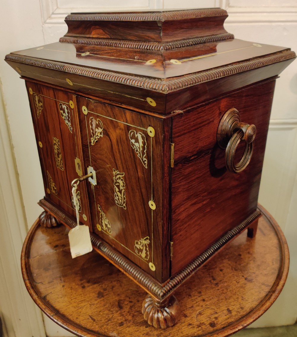 A Georgian dark rosewood tabletop cabinet featuring mother of pearl inlay, a sarcophagus-shaped top, side brass handles, and carved feet. View VI