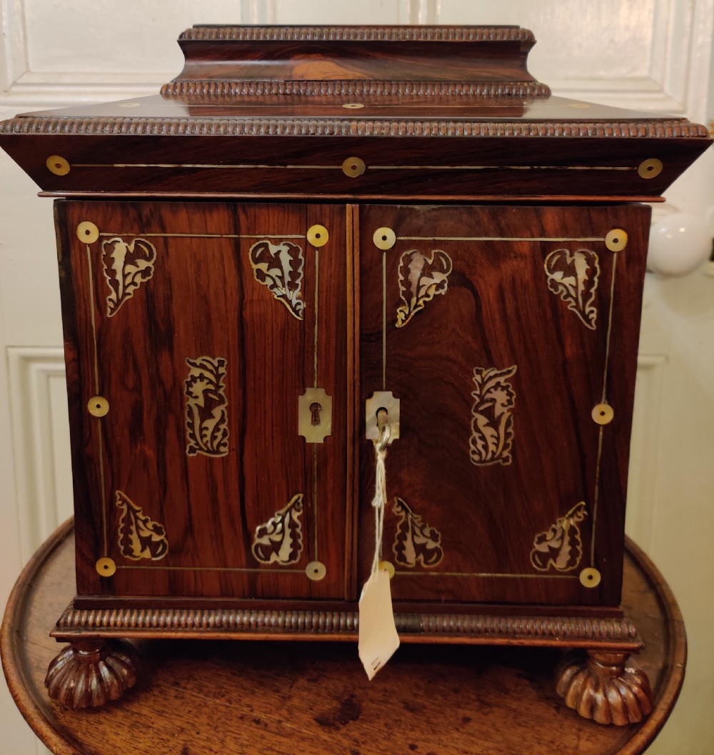 A Georgian dark rosewood tabletop cabinet featuring mother of pearl inlay, a sarcophagus-shaped top, side brass handles, and carved feet. View XIII
