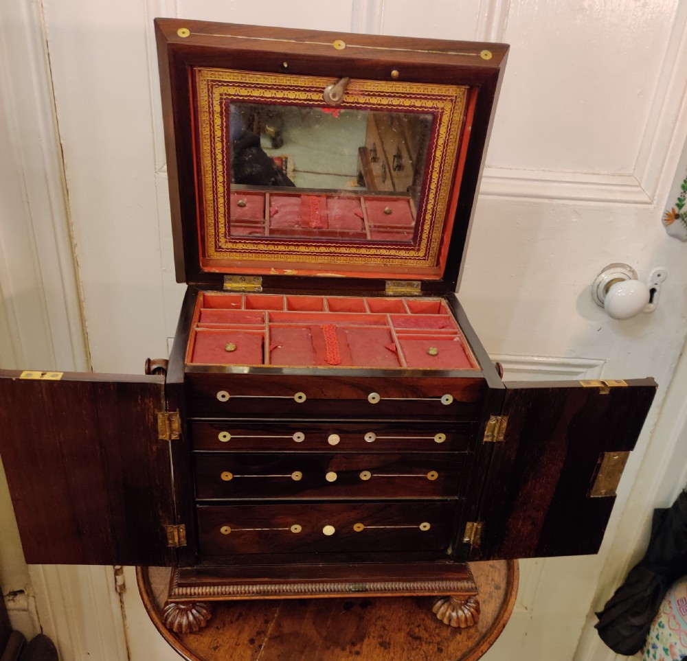 A Georgian dark rosewood tabletop cabinet featuring mother of pearl inlay, a sarcophagus-shaped top, side brass handles, and carved feet. View XX