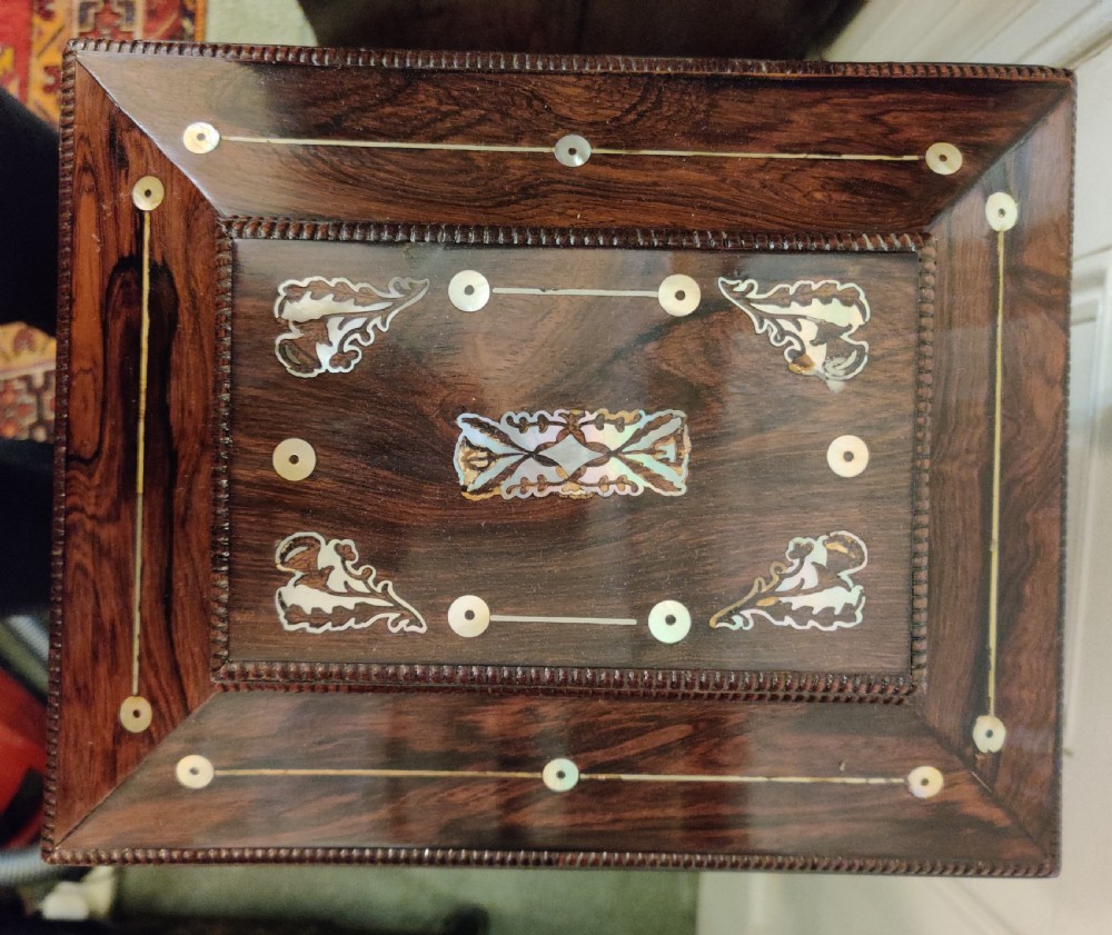 A Georgian dark rosewood tabletop cabinet featuring mother of pearl inlay, a sarcophagus-shaped top, side brass handles, and carved feet. View XXI