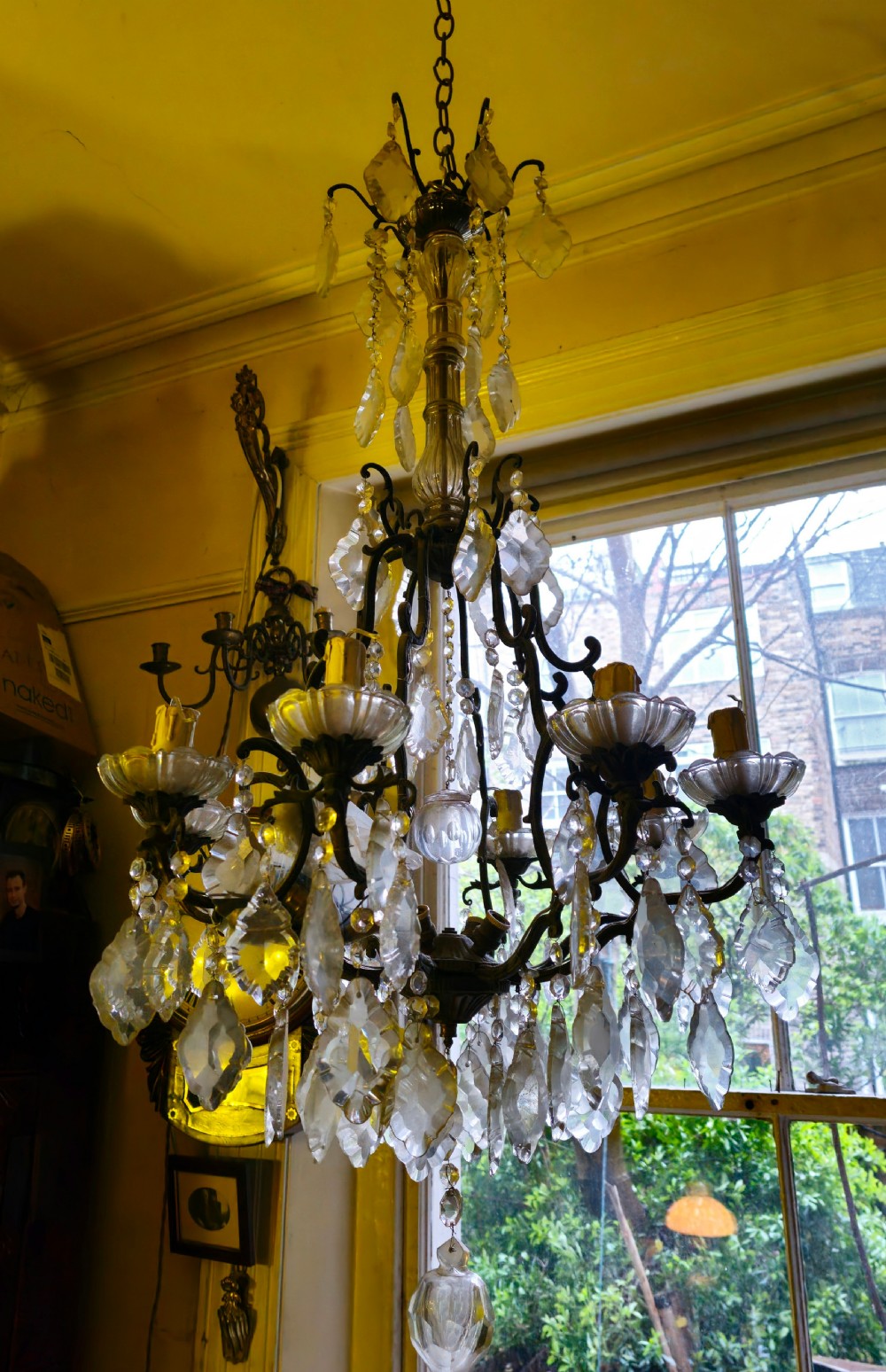 A French circa 1910 multi-tiered chandelier featuring dark metal scrollwork, scalloped glass bobeches, and numerous faceted cut-glass drops. View V