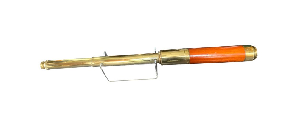 A vintage multi-draw marine telescope featuring a polished brass body and a rich mahogany barrel section, resting horizontally on a clear support stand.