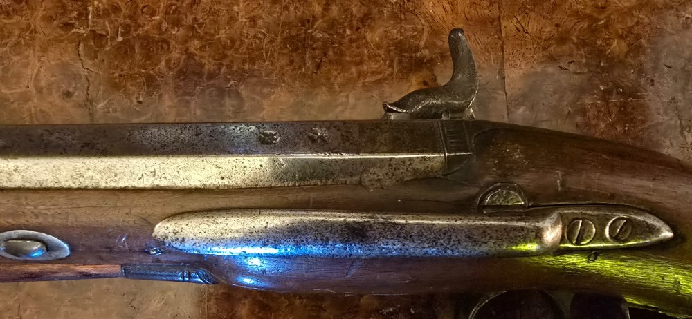 An 1840s percussion belt pistol featuring an engraved steel lockplate, octagonal barrel, and a carved walnut stock with a cross-hatched grip. View III