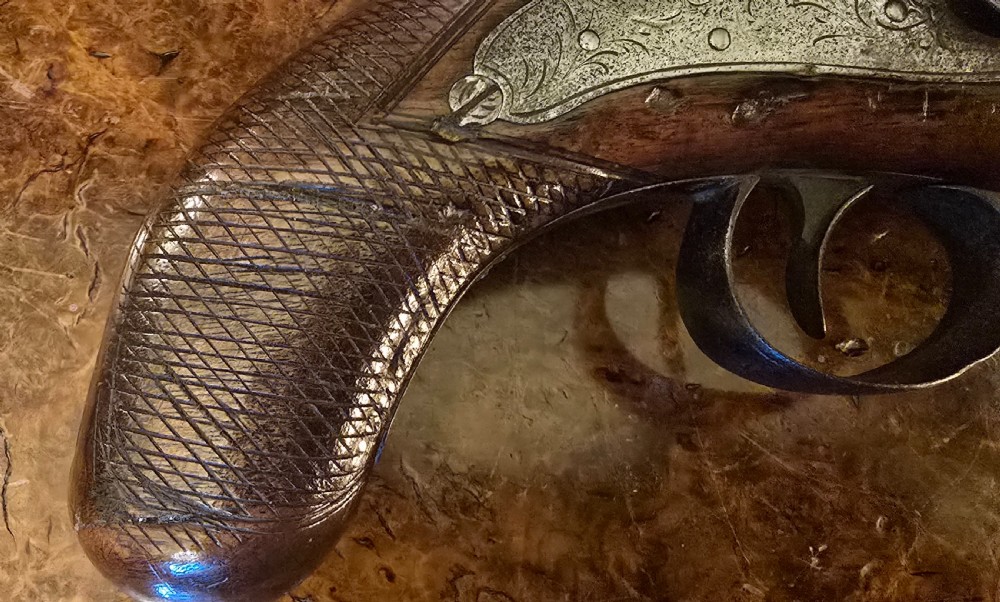 An 1840s percussion belt pistol featuring an engraved steel lockplate, octagonal barrel, and a carved walnut stock with a cross-hatched grip. View V