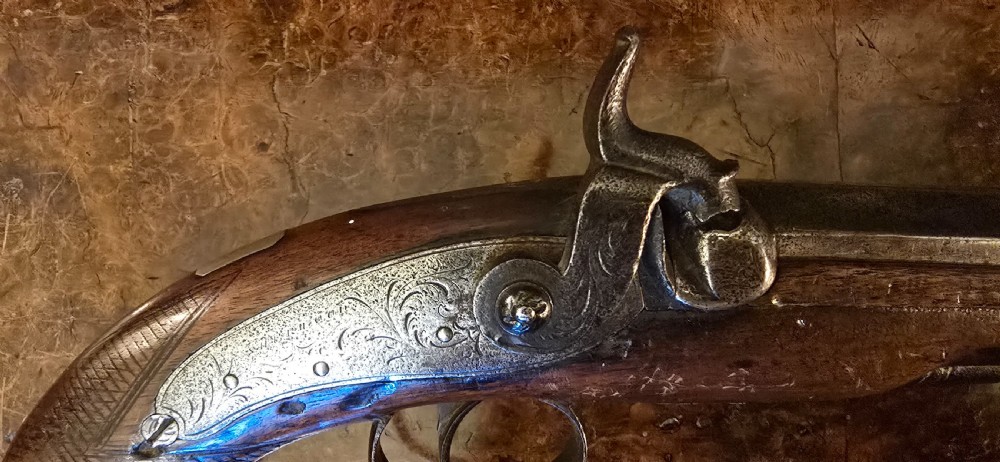 An 1840s percussion belt pistol featuring an engraved steel lockplate, octagonal barrel, and a carved walnut stock with a cross-hatched grip. View XV