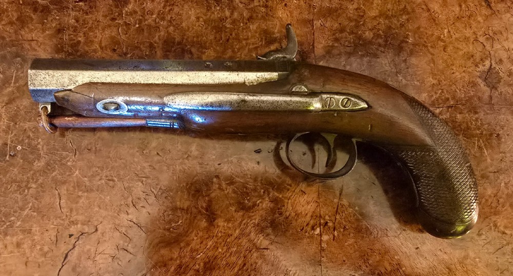 An 1840s percussion belt pistol featuring an engraved steel lockplate, octagonal barrel, and a carved walnut stock with a cross-hatched grip. View XIX