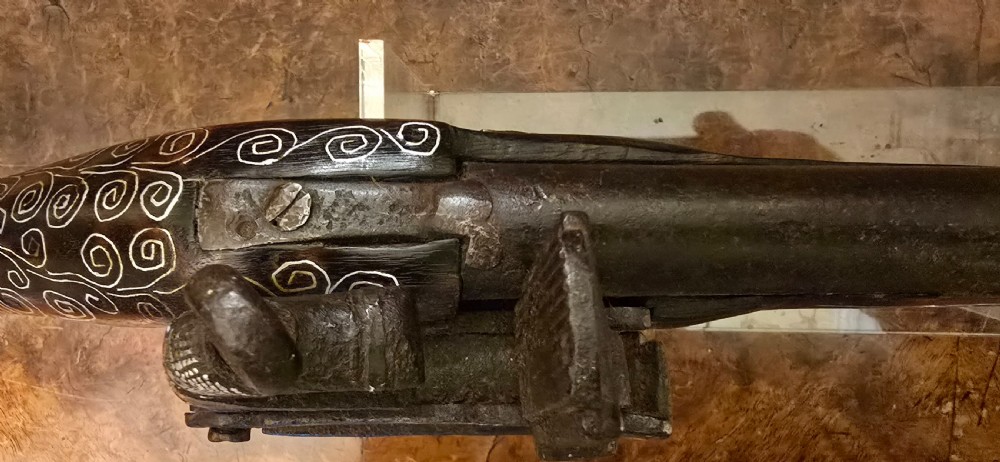 An antique dark wood snaphaunce flintlock pistol featuring intricate silver wire scrollwork inlay along the stock and a steel ignition mechanism. View XXI