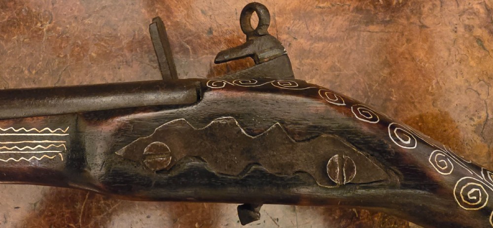 An antique dark wood snaphaunce flintlock pistol featuring intricate silver wire scrollwork inlay along the stock and a steel ignition mechanism. View XXIX