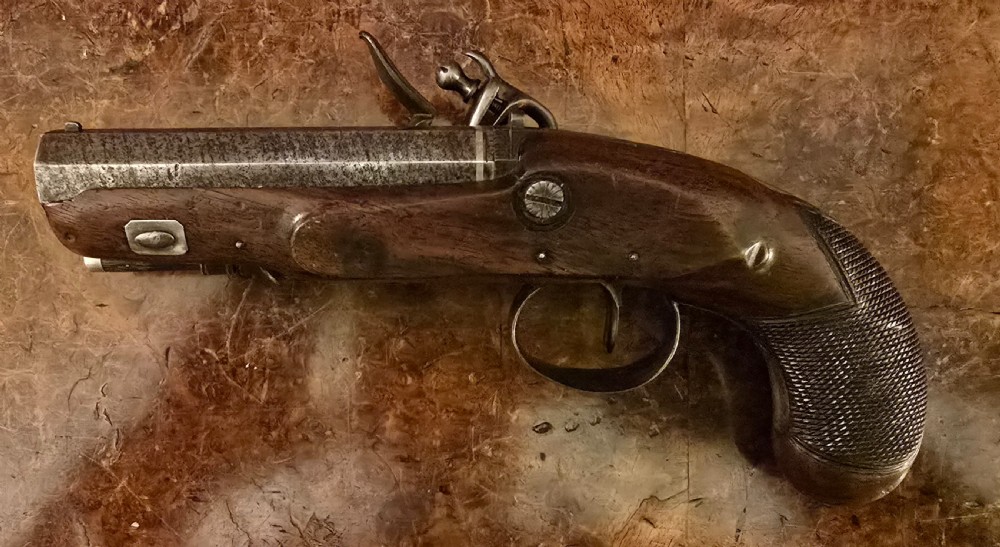 A Georgian British flintlock pocket pistol with a short octagonal barrel. Silver band & cartouche (not hallmarked), by 
Sutherland of London.  View XVII