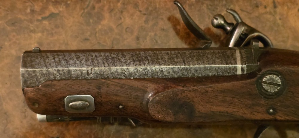 A Georgian British flintlock pocket pistol with a short octagonal barrel. Silver band & cartouche (not hallmarked), by 
Sutherland of London.  View XIX