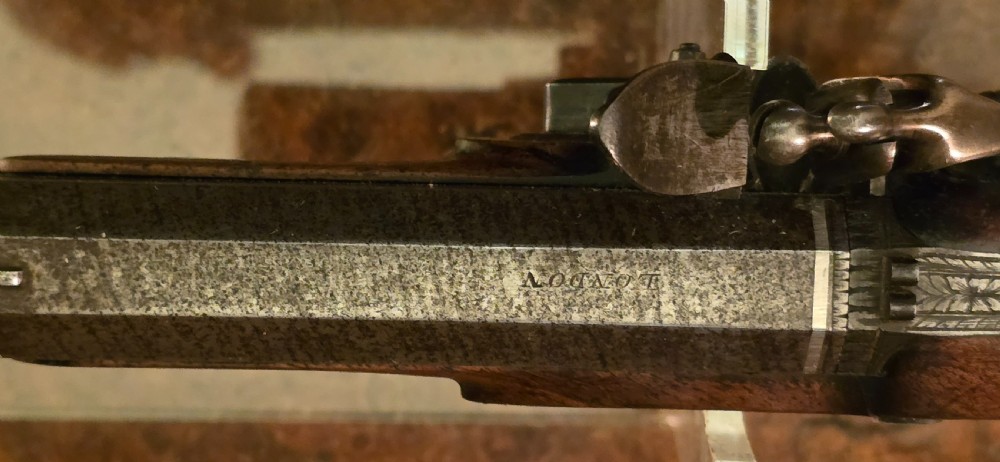 A Georgian British flintlock pocket pistol with a short octagonal barrel. Silver band & cartouche (not hallmarked), by 
Sutherland of London.  View XXVI