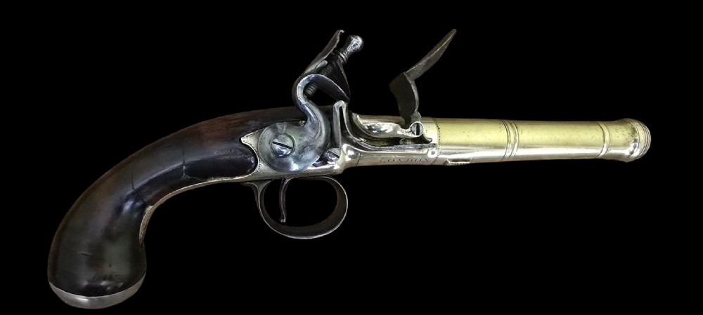 A pair of 18th-century English flintlock turn-off pistols featuring brass cannon barrels, steel lock mechanisms, and smooth walnut stocks. View II