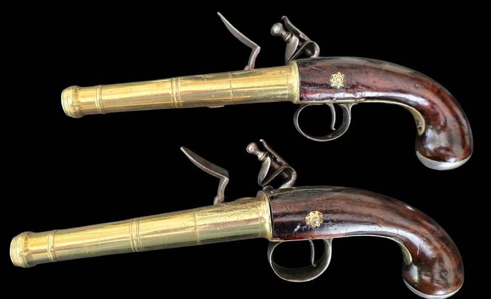 A pair of 18th-century English flintlock turn-off pistols featuring brass cannon barrels, steel lock mechanisms, and smooth walnut stocks. View III