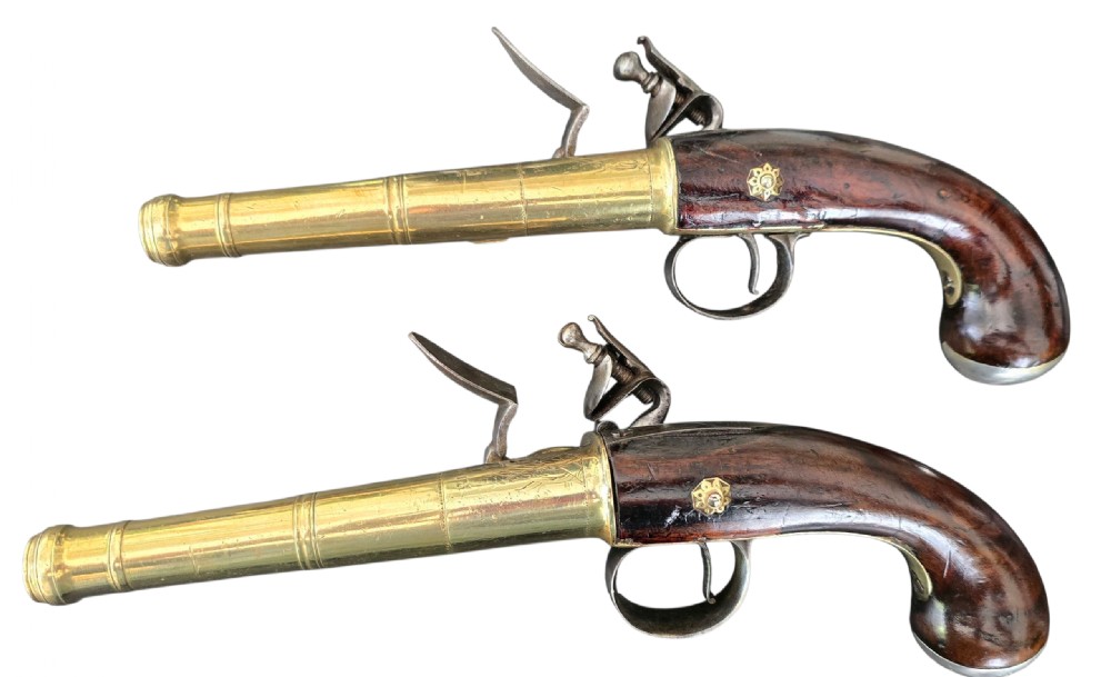A pair of 18th-century English flintlock turn-off pistols featuring brass cannon barrels, steel lock mechanisms, and smooth walnut stocks. View IX