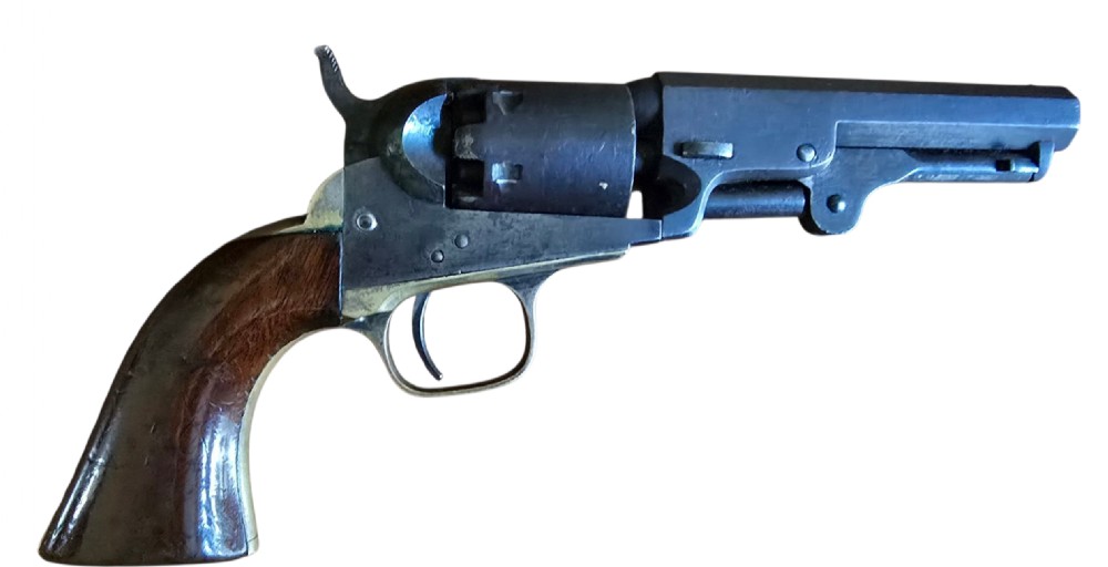 An antique Colt Model 1849 pocket revolver with an octagonal dark steel barrel, smooth walnut grip, and brass trigger guard.
