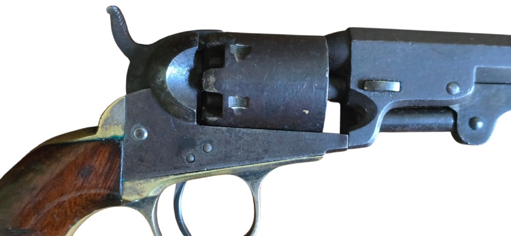 An antique Colt Model 1849 pocket revolver with an octagonal dark steel barrel, smooth walnut grip, and brass trigger guard. View II