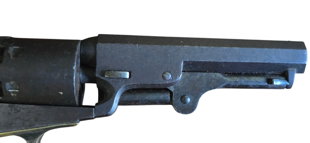 An antique Colt Model 1849 pocket revolver with an octagonal dark steel barrel, smooth walnut grip, and brass trigger guard. View III