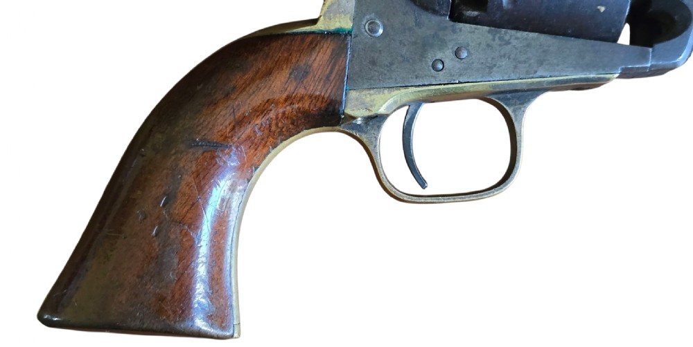 An antique Colt Model 1849 pocket revolver with an octagonal dark steel barrel, smooth walnut grip, and brass trigger guard. View V