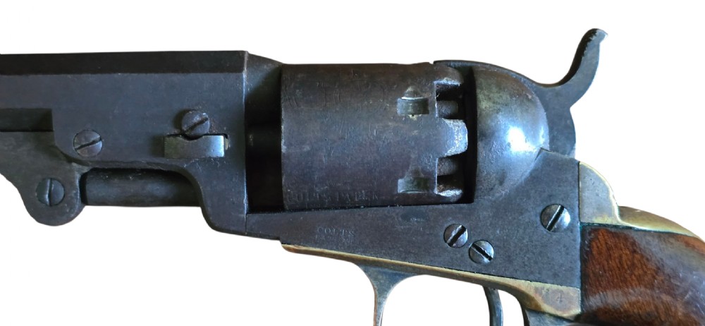 An antique Colt Model 1849 pocket revolver with an octagonal dark steel barrel, smooth walnut grip, and brass trigger guard. View IX
