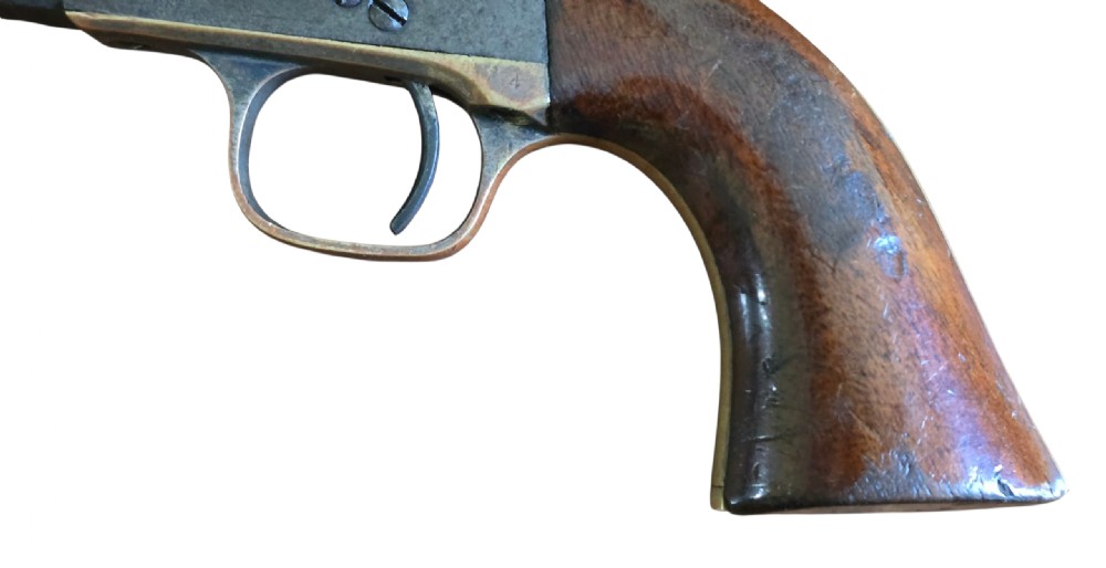 An antique Colt Model 1849 pocket revolver with an octagonal dark steel barrel, smooth walnut grip, and brass trigger guard. View XII