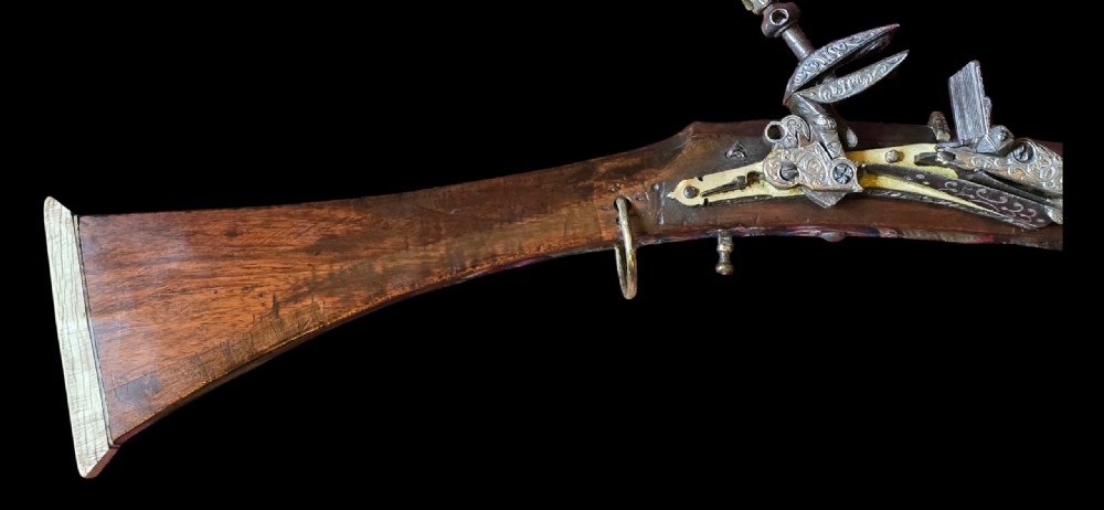 An 18th century Ottoman Algerian toe-lock long gun featuring a slender wooden stock decorated with brass bands and bone inlays. View V