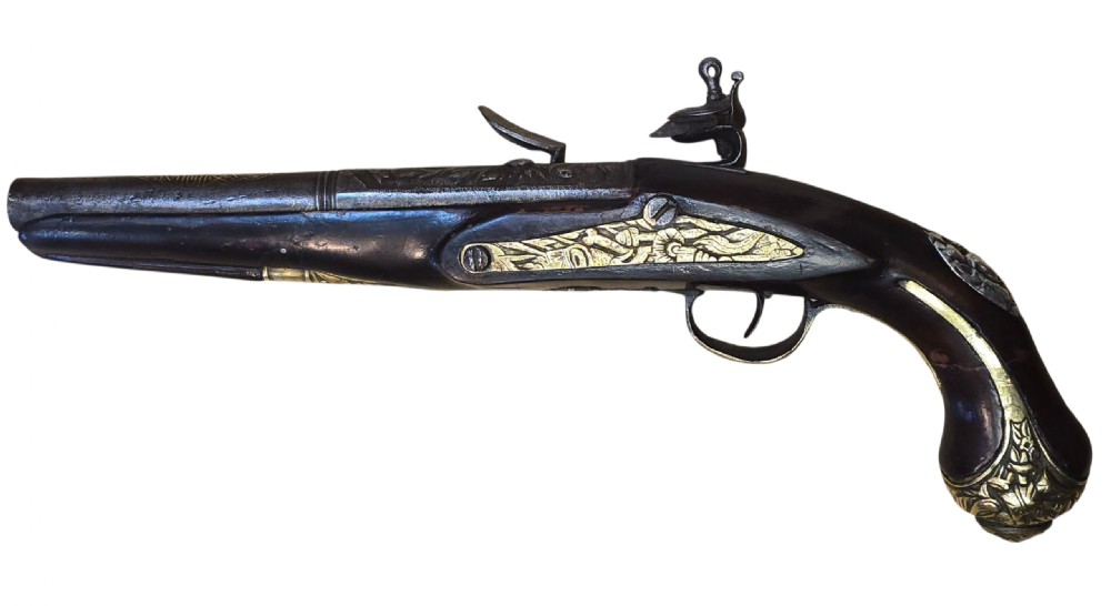 An antique Ottoman flintlock pistol featuring a dark carved wooden stock inlaid with silver accents and a steel barrel with gilt detailing. View VI