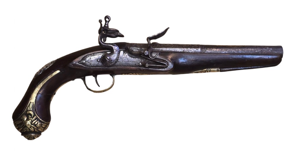 An antique Ottoman flintlock pistol featuring a dark carved wooden stock inlaid with silver accents and a steel barrel with gilt detailing. View X