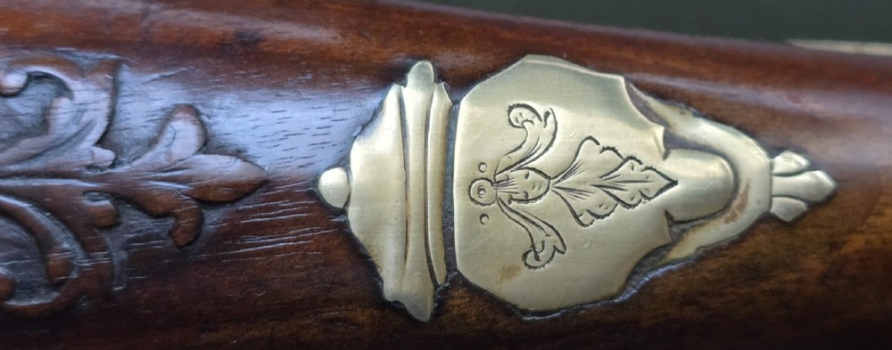 An 18th-century French flintlock holster pistol featuring a carved walnut stock, polished brass barrel, engraved brass lockplate, and steel mechanism. View XIII
