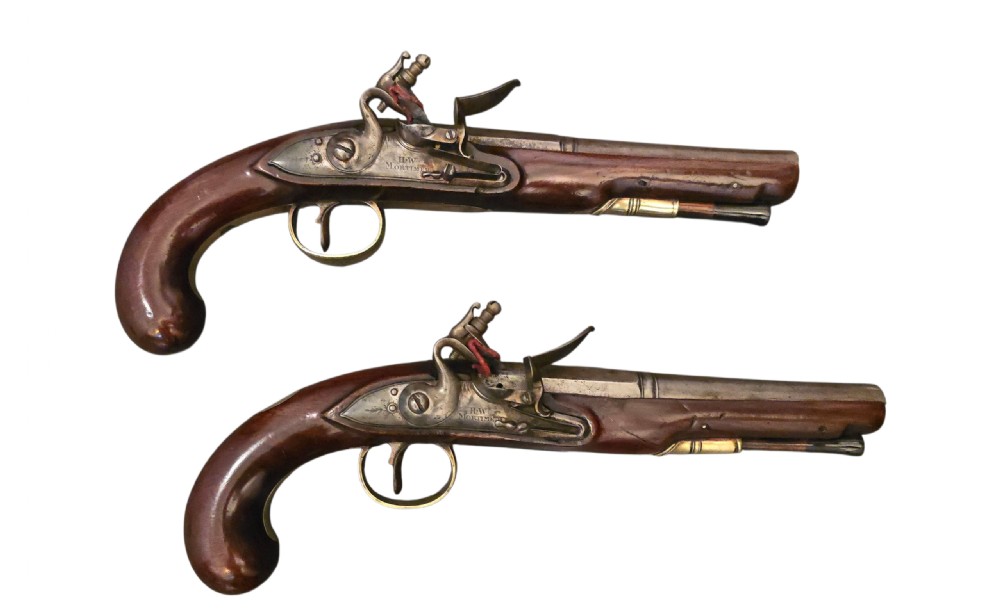 A fitted mahogany wooden case lined with green baize containing a pair of flintlock duelling pistols, a ramrod, and loading accessories. View VI