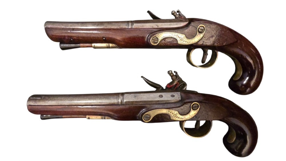 A fitted mahogany wooden case lined with green baize containing a pair of flintlock duelling pistols, a ramrod, and loading accessories. View VII