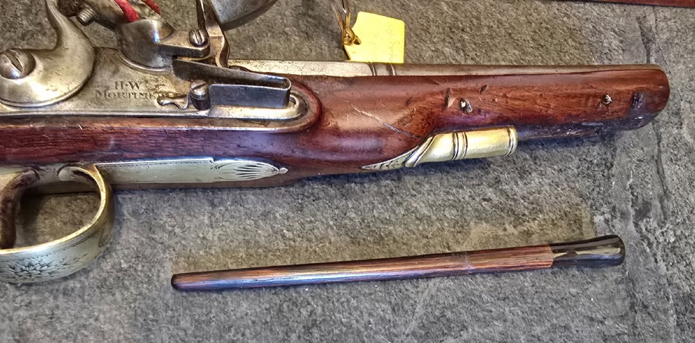 A fitted mahogany wooden case lined with green baize containing a pair of flintlock duelling pistols, a ramrod, and loading accessories. View IX