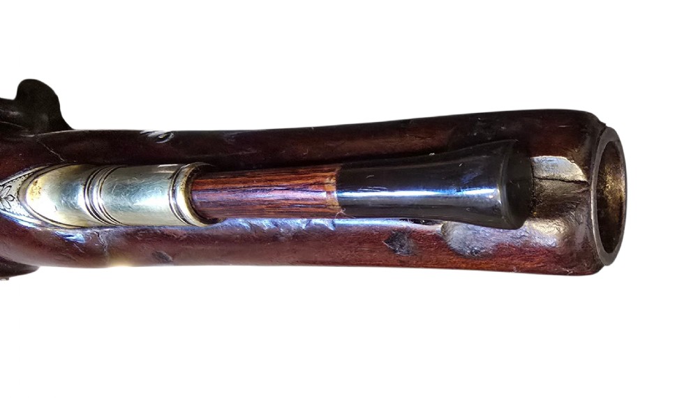 A fitted mahogany wooden case lined with green baize containing a pair of flintlock duelling pistols, a ramrod, and loading accessories. View X
