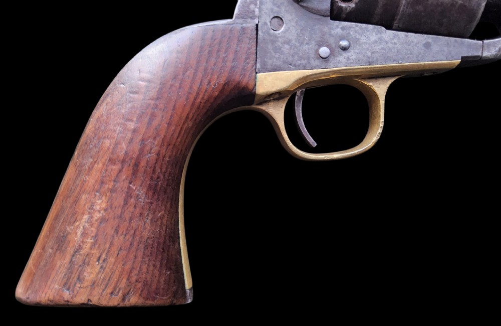 Side profile of a patinated steel Colt Model 1860 Army percussion revolver featuring a walnut handle grip and brass trigger guard. View IV