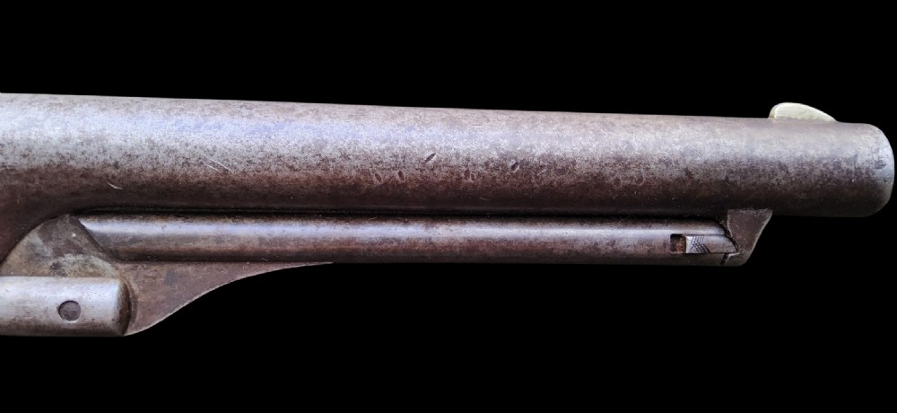 Side profile of a patinated steel Colt Model 1860 Army percussion revolver featuring a walnut handle grip and brass trigger guard. View V