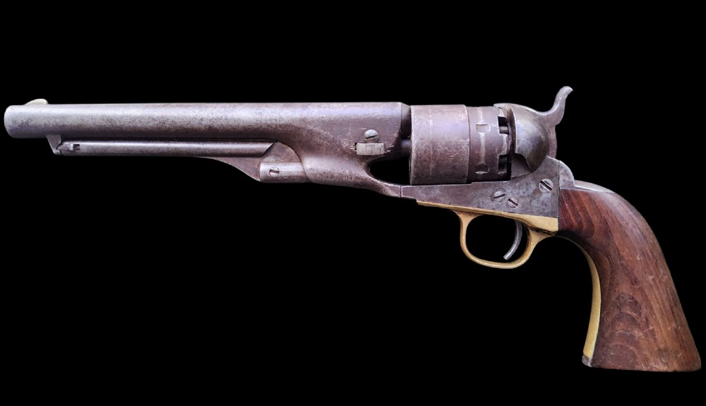 Side profile of a patinated steel Colt Model 1860 Army percussion revolver featuring a walnut handle grip and brass trigger guard. View VI