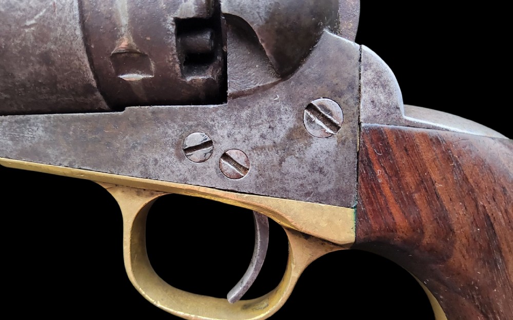 Side profile of a patinated steel Colt Model 1860 Army percussion revolver featuring a walnut handle grip and brass trigger guard. View VIII