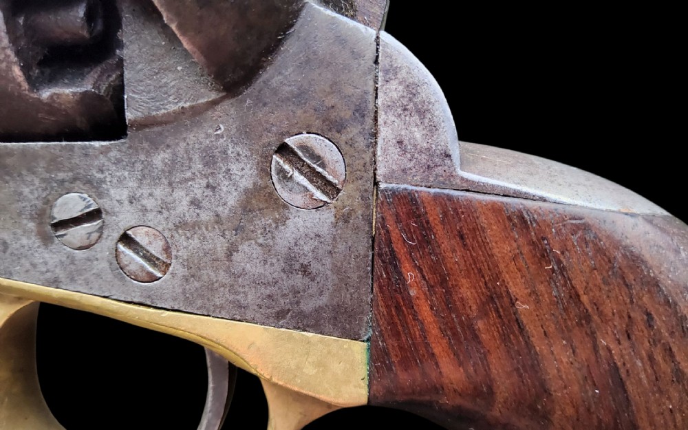 Side profile of a patinated steel Colt Model 1860 Army percussion revolver featuring a walnut handle grip and brass trigger guard. View XI