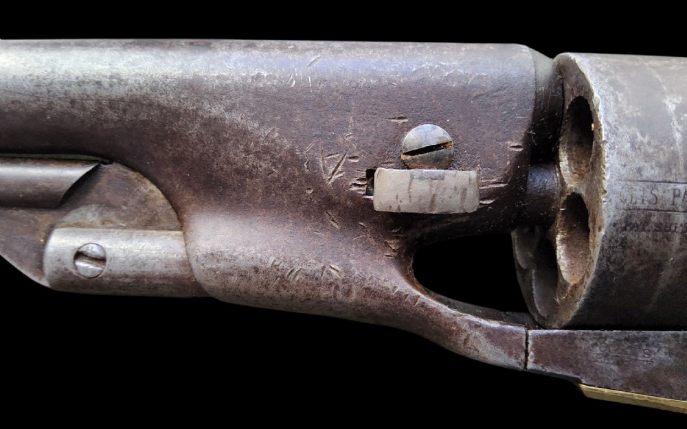 Side profile of a patinated steel Colt Model 1860 Army percussion revolver featuring a walnut handle grip and brass trigger guard. View XIV