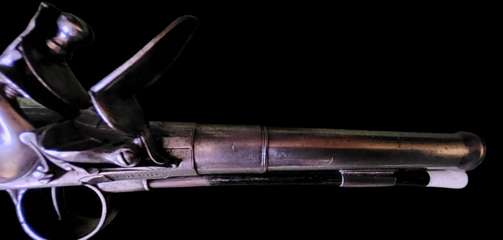 A mid-18th century flintlock pistol featuring a figured walnut stock, steel mechanism, and engraved silver mounts. View II