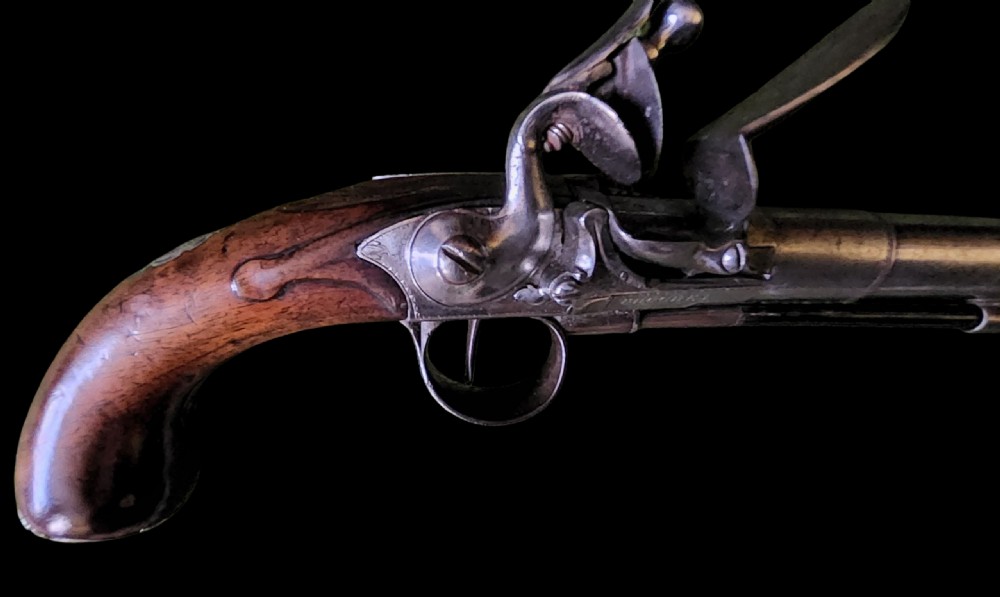 A mid-18th century flintlock pistol featuring a figured walnut stock, steel mechanism, and engraved silver mounts. View III
