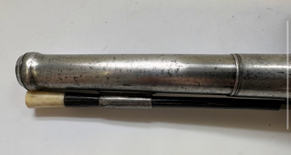 A mid-18th century flintlock pistol featuring a figured walnut stock, steel mechanism, and engraved silver mounts. View XIX