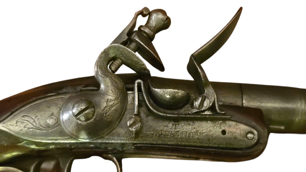 An 18th-century English Queen Anne flintlock turn-off pistol featuring an engraved steel mechanism, round steel barrel, dark walnut stock, and a brass butt cap. View II