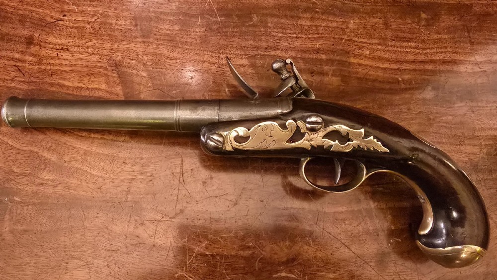 An 18th-century English Queen Anne flintlock turn-off pistol featuring an engraved steel mechanism, round steel barrel, dark walnut stock, and a brass butt cap. View VIII