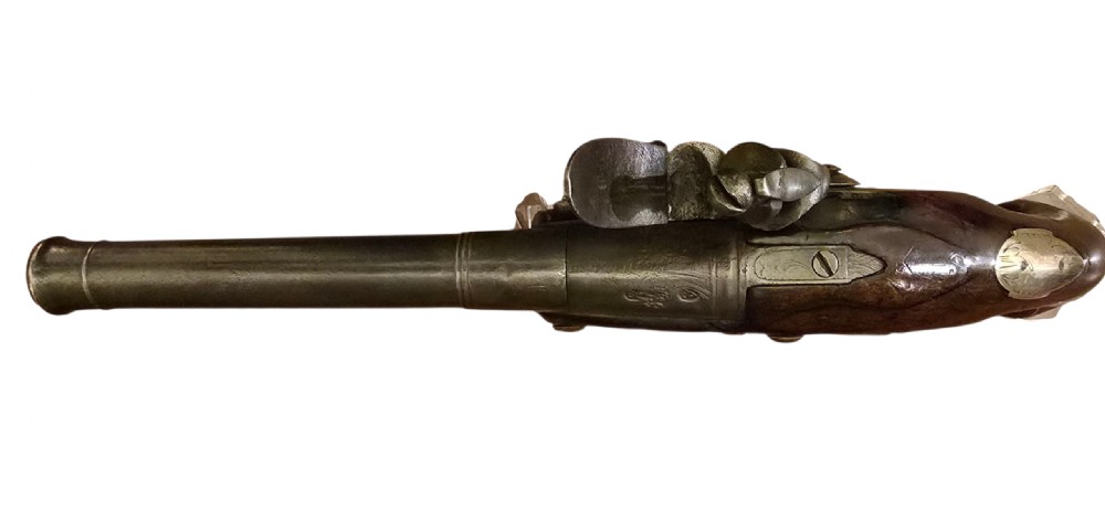 An 18th-century English Queen Anne flintlock turn-off pistol featuring an engraved steel mechanism, round steel barrel, dark walnut stock, and a brass butt cap. View XII
