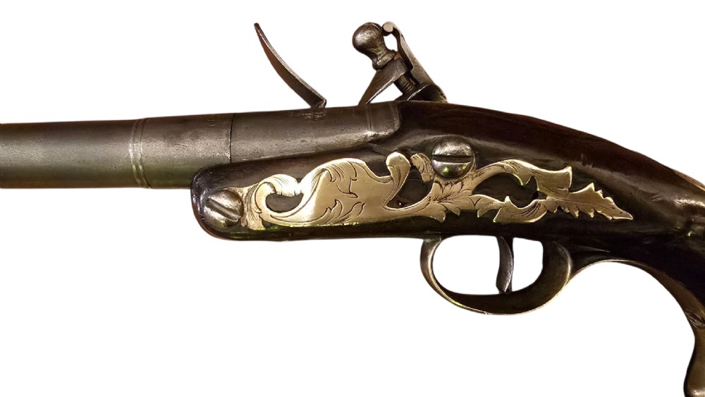 An 18th-century English Queen Anne flintlock turn-off pistol featuring an engraved steel mechanism, round steel barrel, dark walnut stock, and a brass butt cap. View XVI