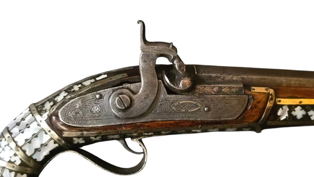 A 19th-century Ottoman pistol featuring a dark wood stock inlaid with mother-of-pearl geometric designs and brass wire, with an engraved steel mechanism and barrel. View VI