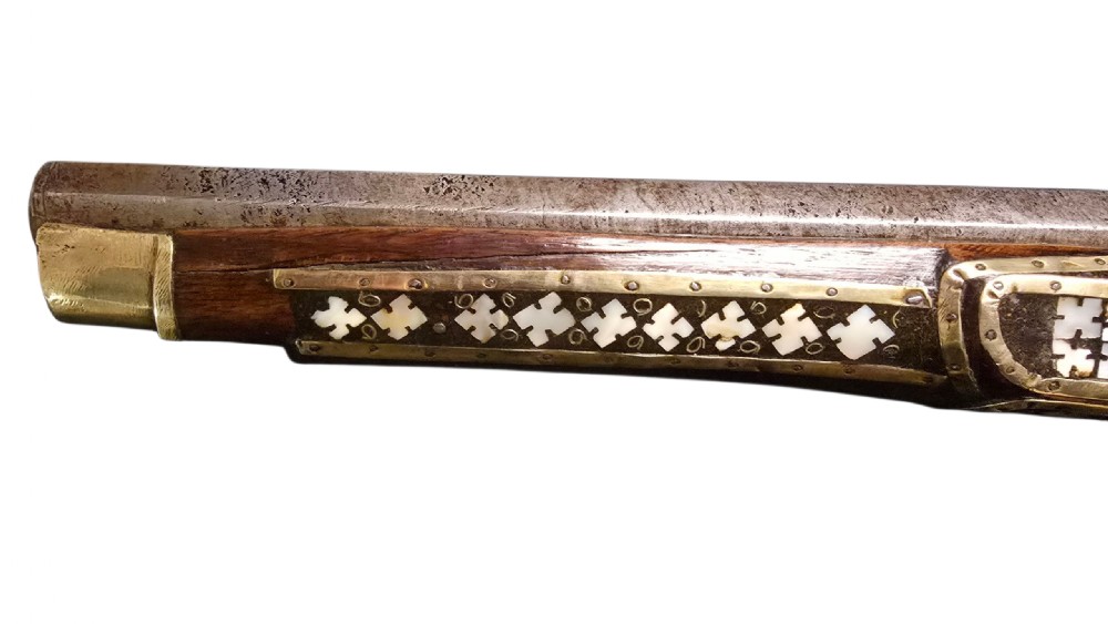 A 19th-century Ottoman pistol featuring a dark wood stock inlaid with mother-of-pearl geometric designs and brass wire, with an engraved steel mechanism and barrel. View VII