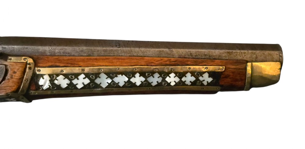 A 19th-century Ottoman pistol featuring a dark wood stock inlaid with mother-of-pearl geometric designs and brass wire, with an engraved steel mechanism and barrel. View IX